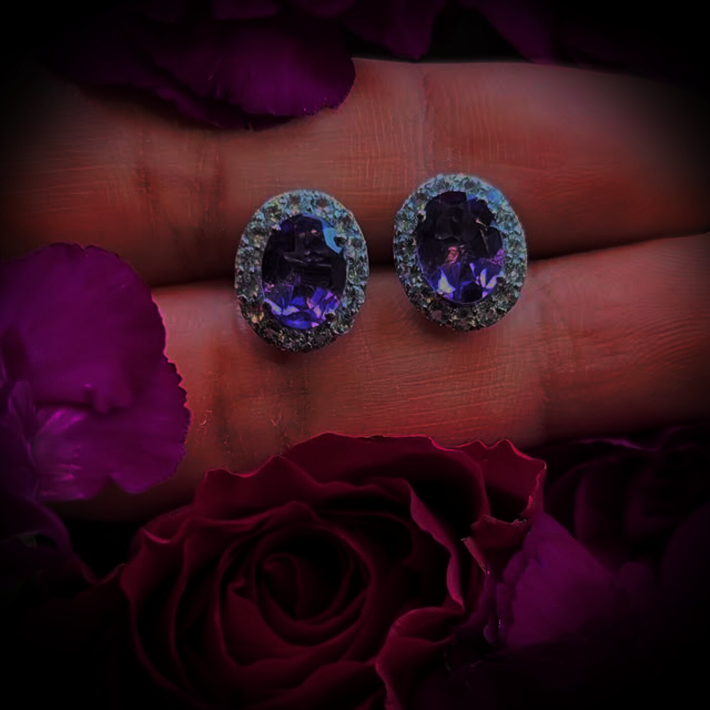 A pair of amethyst drop earrings on a dark ground.