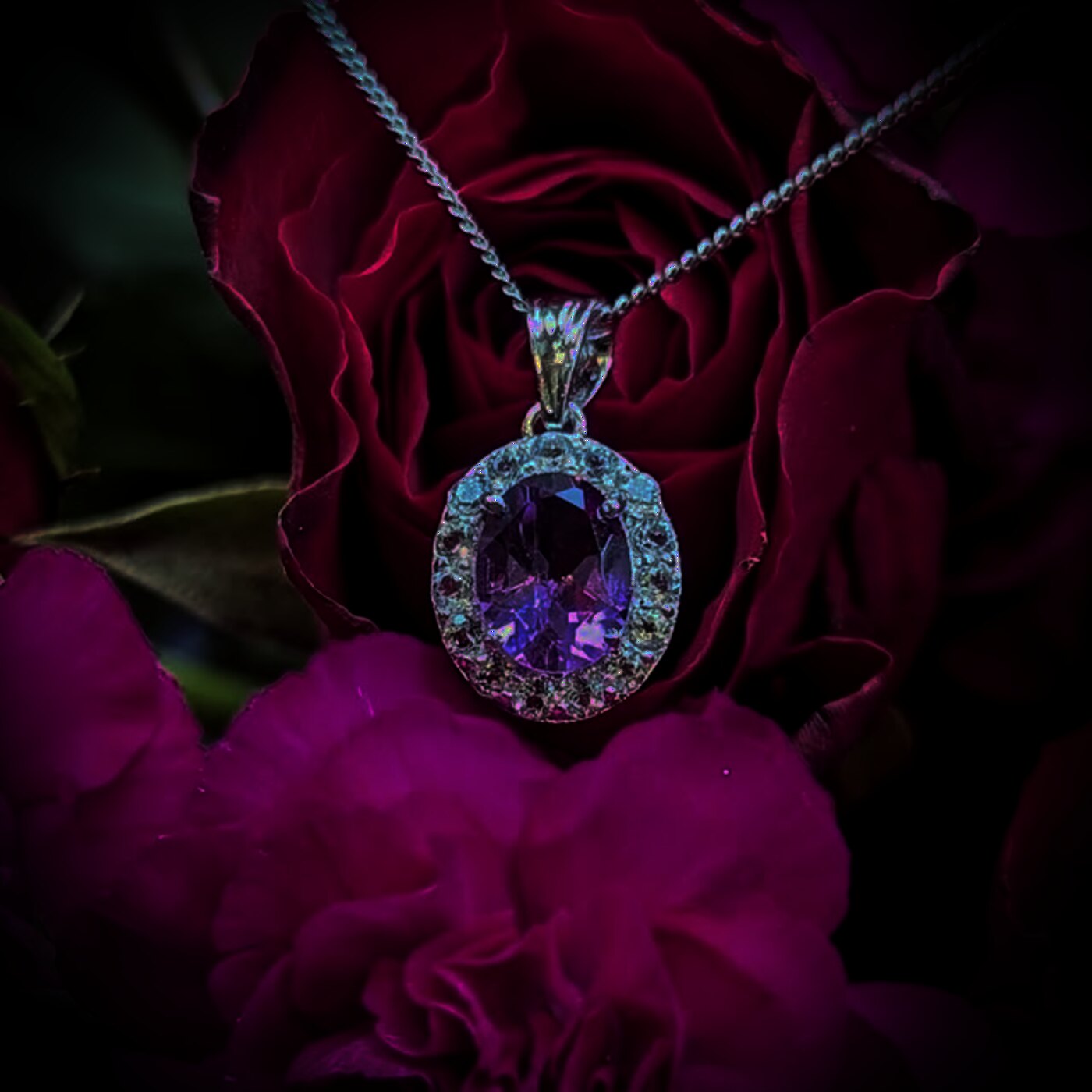 An oval amethyst pendant framed with a halo, on a fine chain.
