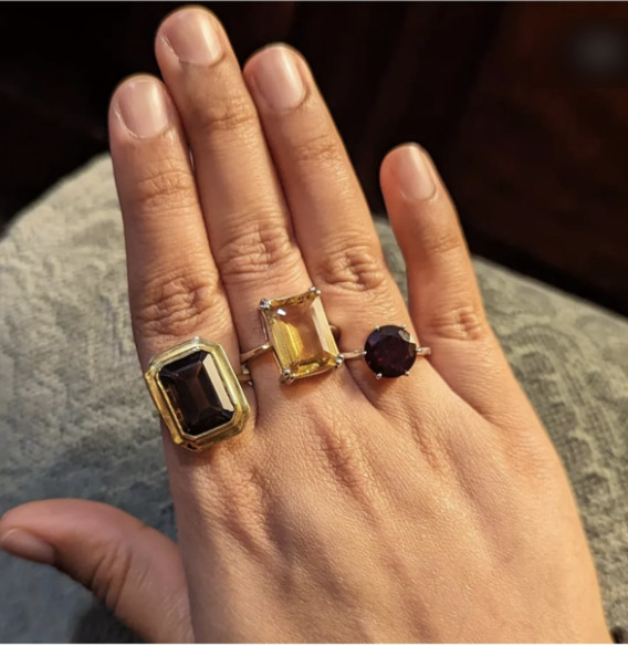 Three gemstone rings worn on a hand in warm light.