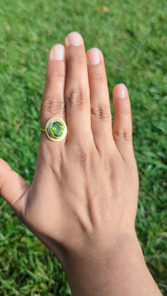 Peridot ring on a hand, styled with natural fabric